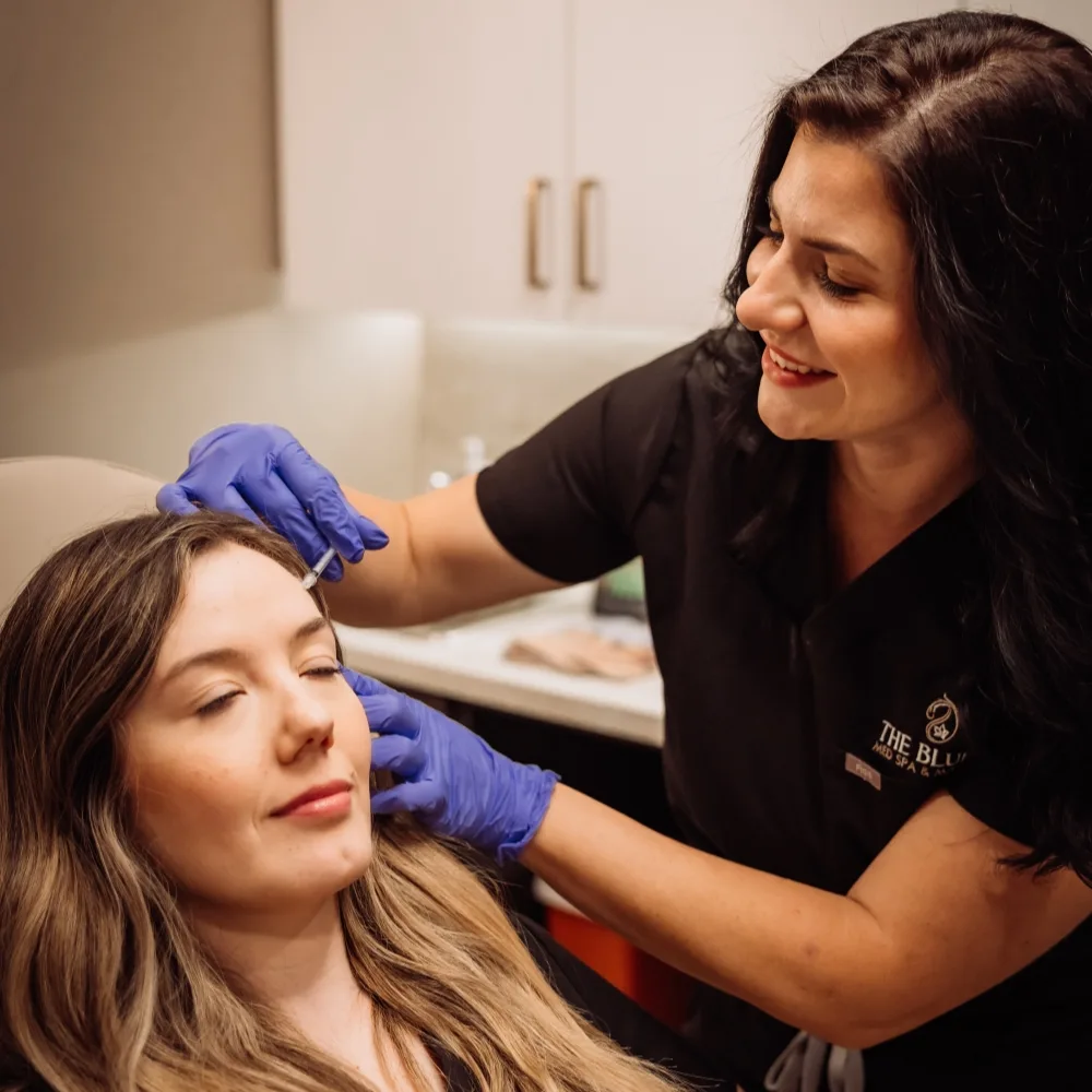 A registered nurse in Bluffs scrubs administering an injectable treatment