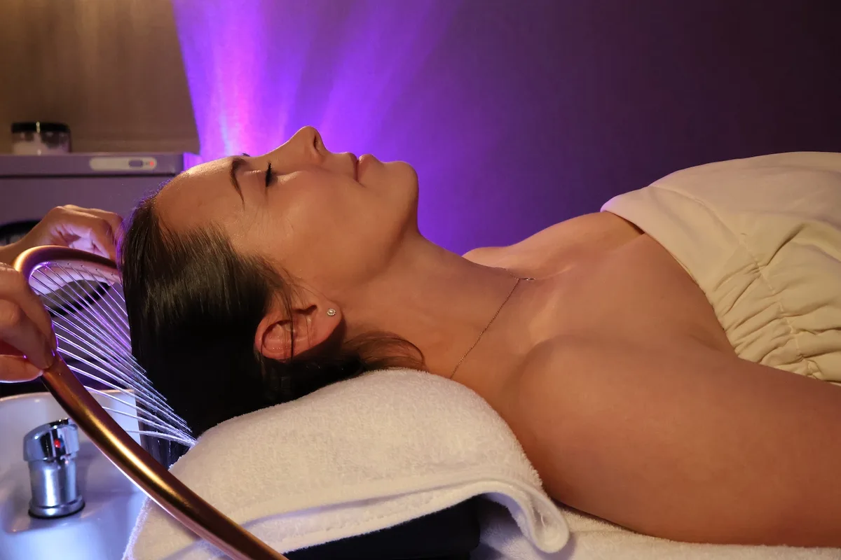 Woman receiving a head spa water treatment under ambient light